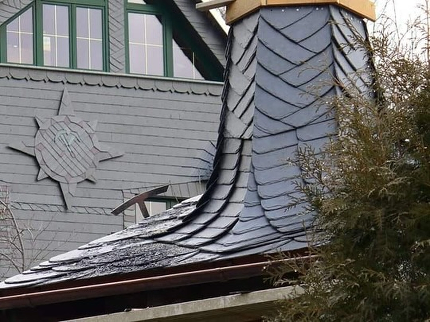 Buczek & Degen Bedachungen GmbH – Dachdeckermeisterbetrieb – ein traditionelles Dach im europäischen Stil, verziert mit Naturschieferziegeln in einem dekorativen, überlappenden Muster